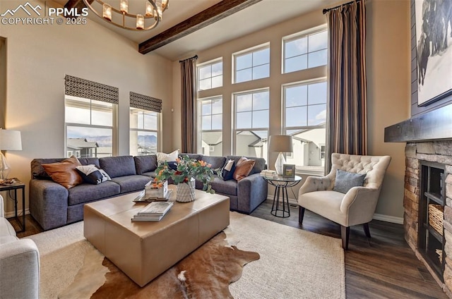 living area featuring baseboards, dark wood-style floors, beamed ceiling, a fireplace, and a chandelier