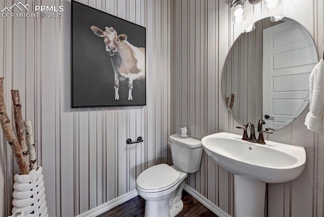 bathroom with baseboards, a sink, toilet, and wood finished floors