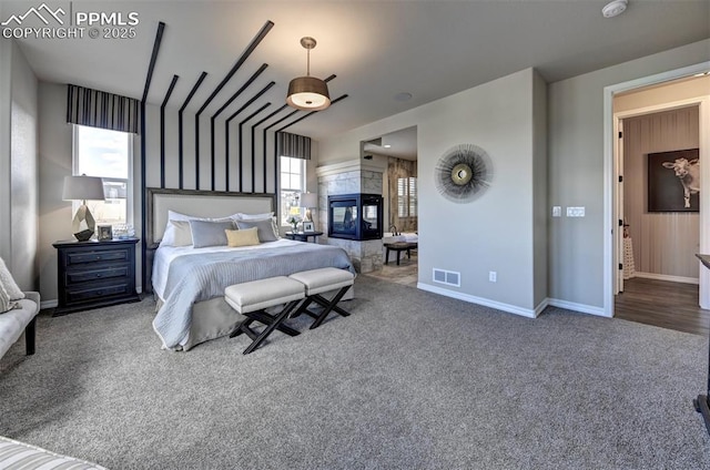 bedroom with carpet, a tiled fireplace, visible vents, and baseboards