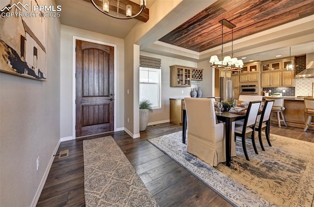 entrance foyer featuring an inviting chandelier, baseboards, a raised ceiling, and dark wood finished floors