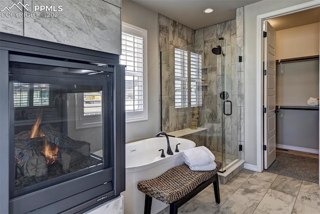 full bathroom with a bathing tub, baseboards, marble finish floor, a spacious closet, and a shower stall