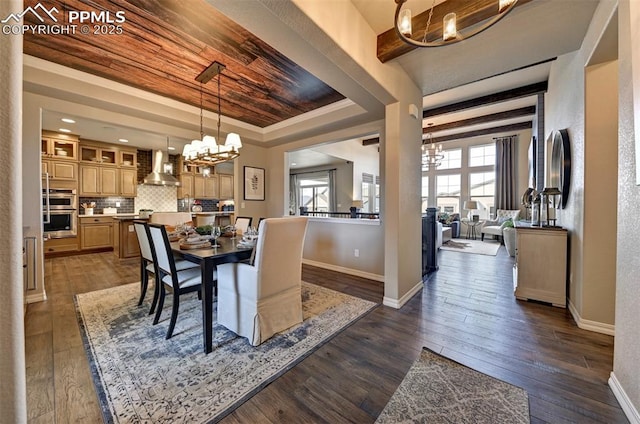 dining space featuring dark wood-style floors, a tray ceiling, crown molding, a notable chandelier, and baseboards