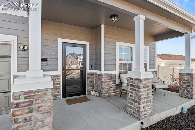 entrance to property with a porch and stone siding