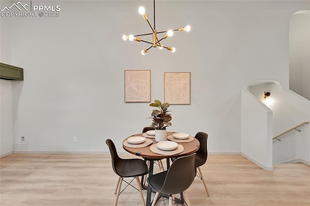 dining space featuring light wood-style floors, baseboards, a chandelier, and a wall mounted AC