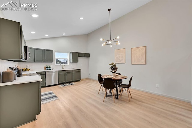 kitchen featuring stainless steel appliances, a sink, light countertops, light wood-type flooring, and an inviting chandelier