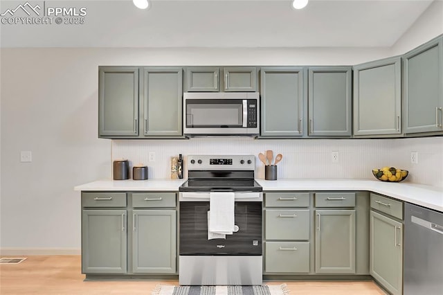 kitchen featuring stainless steel appliances, visible vents, light countertops, light wood-type flooring, and green cabinetry