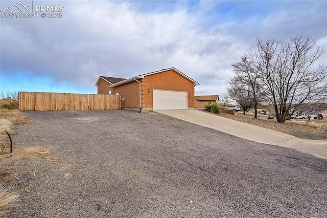 view of home's exterior featuring driveway, a garage, and fence