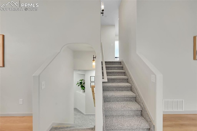 staircase featuring baseboards, visible vents, and wood finished floors