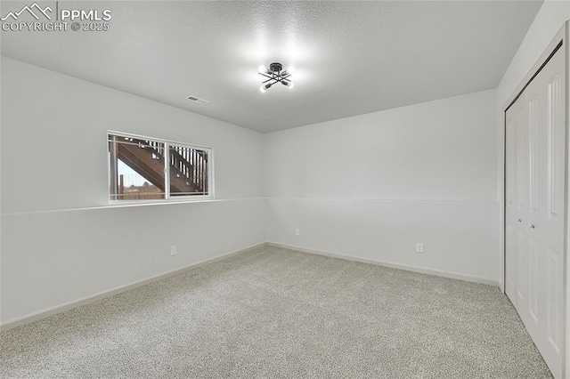 unfurnished bedroom with visible vents, baseboards, a textured ceiling, carpet floors, and a closet