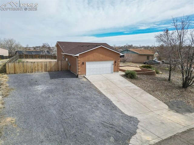 ranch-style house with fence, driveway, an attached garage, and stucco siding