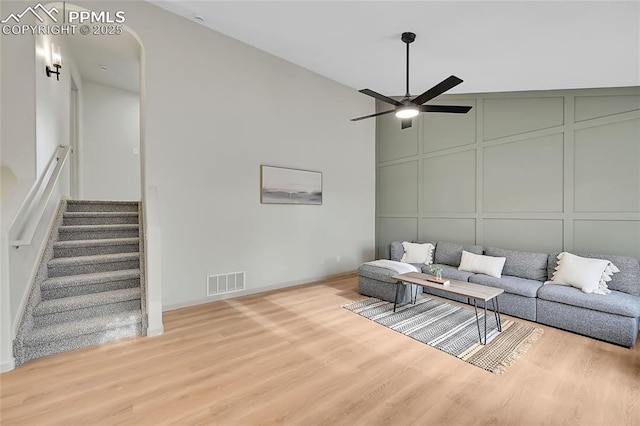 living room featuring stairway, wood finished floors, visible vents, and a decorative wall