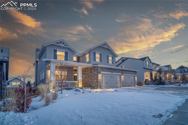 view of front of house with a garage, driveway, stone siding, covered porch, and stucco siding