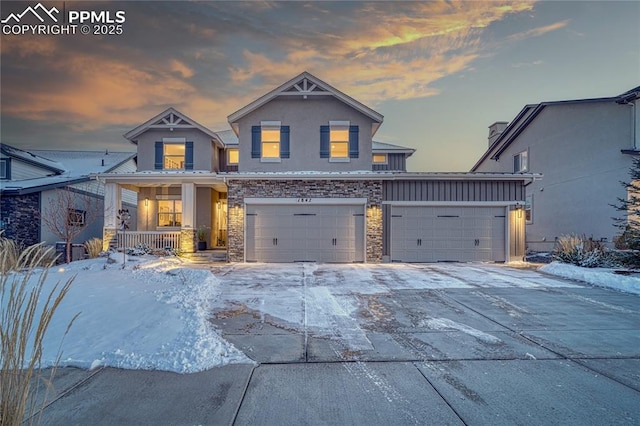 view of front of home featuring a porch, stone siding, concrete driveway, stucco siding, and board and batten siding