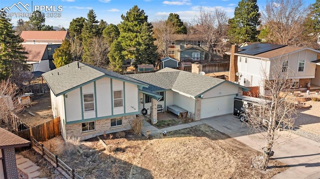 view of front of property featuring a shingled roof, concrete driveway, fence, a garage, and a residential view