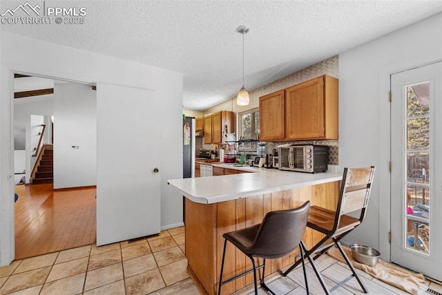 kitchen with light tile patterned floors, a textured ceiling, light countertops, decorative backsplash, and a kitchen bar