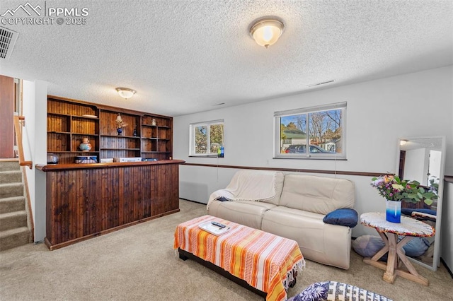 carpeted living room featuring a textured ceiling, stairway, and visible vents