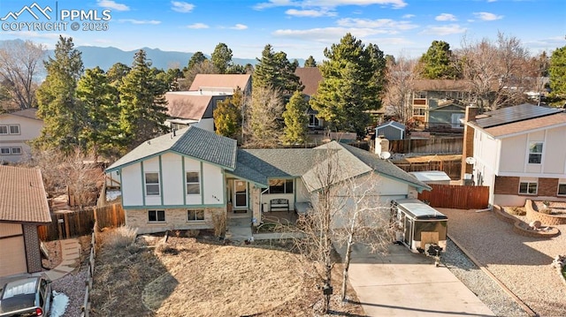 view of front of home featuring a mountain view, concrete driveway, fence, and a residential view