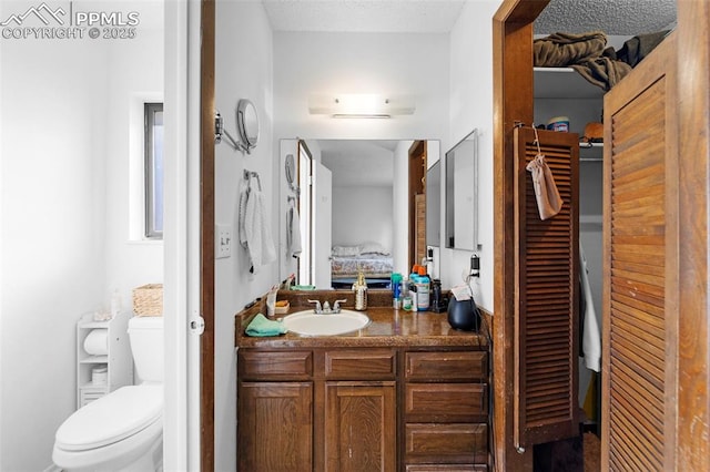 ensuite bathroom with toilet, ensuite bath, a walk in closet, and vanity