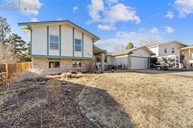 split level home featuring concrete driveway, brick siding, an attached garage, and fence