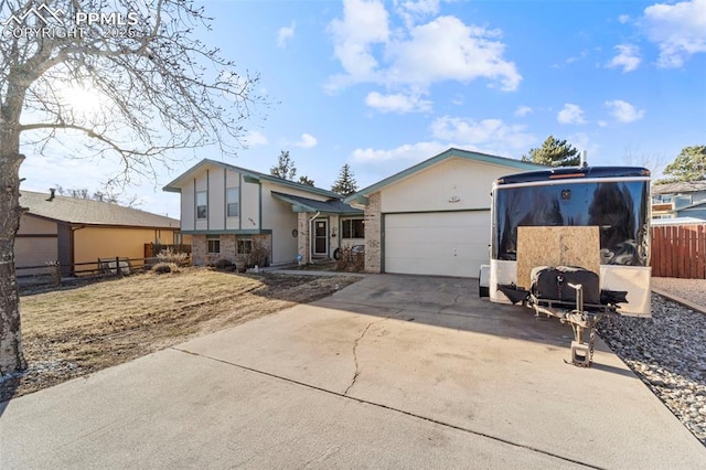 view of front of home with concrete driveway, brick siding, an attached garage, and fence