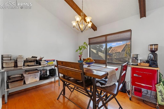 dining area featuring lofted ceiling with beams, wood finished floors, and a chandelier