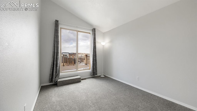 carpeted empty room featuring baseboards and vaulted ceiling