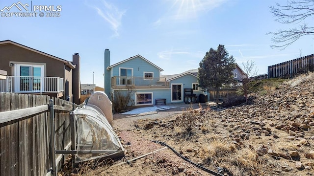 rear view of house featuring a chimney, fence, a balcony, and a patio