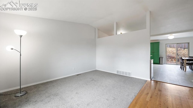 spare room featuring visible vents, vaulted ceiling, and wood finished floors