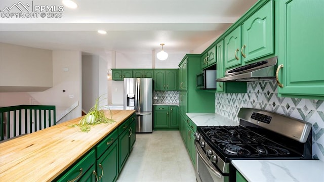 kitchen with under cabinet range hood, butcher block counters, appliances with stainless steel finishes, tasteful backsplash, and green cabinetry