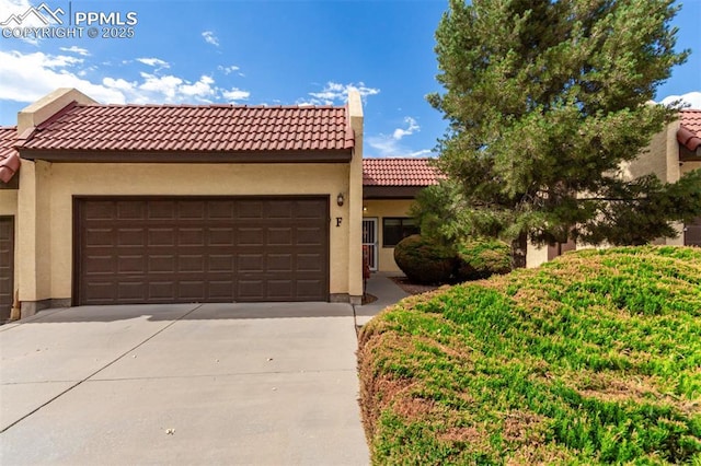 view of front facade with driveway, an attached garage, a tiled roof, and stucco siding