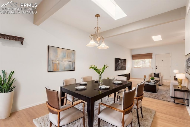 dining space featuring a skylight, light wood-style flooring, a chandelier, beamed ceiling, and baseboards