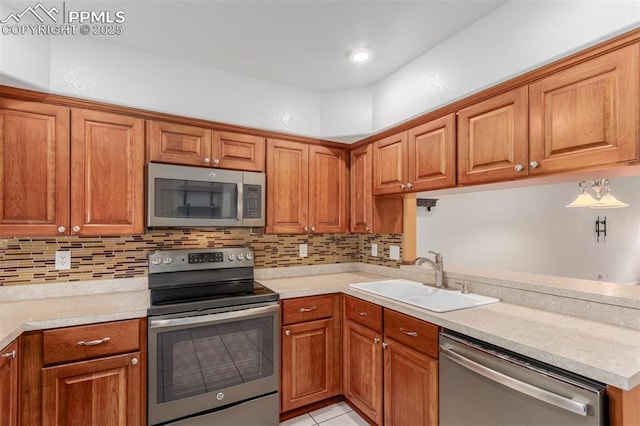 kitchen featuring tasteful backsplash, light countertops, appliances with stainless steel finishes, brown cabinetry, and a sink