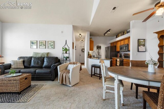 living room featuring a ceiling fan, rail lighting, visible vents, and light carpet