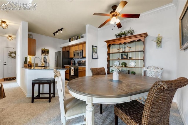 dining room featuring light carpet, baseboards, ceiling fan, crown molding, and track lighting