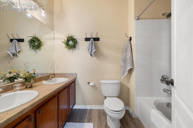 bathroom featuring tub / shower combination, a sink, toilet, and wood finished floors