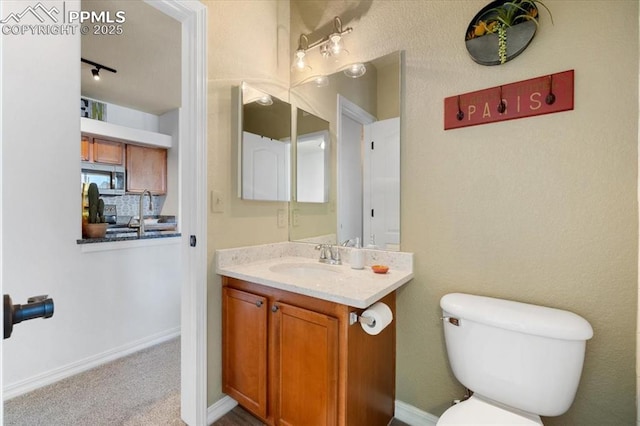 half bathroom featuring decorative backsplash, vanity, toilet, and baseboards