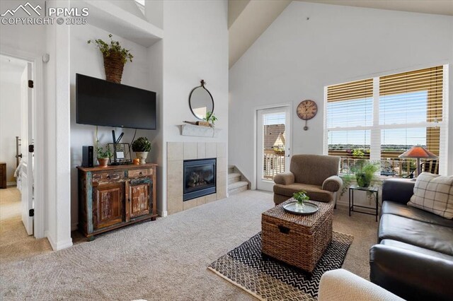 carpeted living room with high vaulted ceiling and a tile fireplace