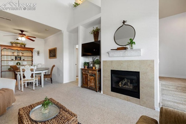 living room with ceiling fan, a fireplace, carpet flooring, visible vents, and ornamental molding