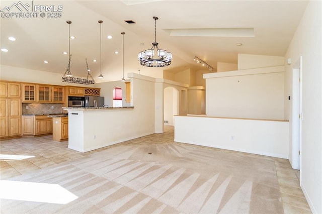 kitchen featuring glass insert cabinets, a chandelier, open floor plan, decorative backsplash, and fridge