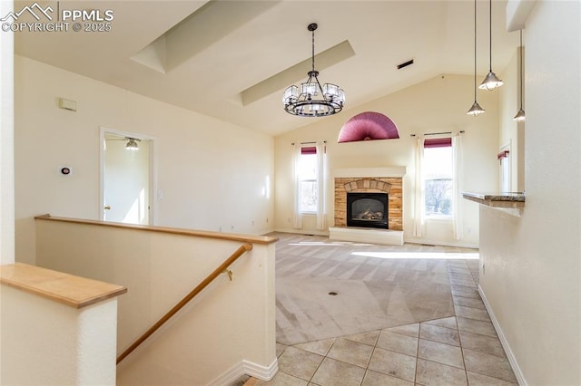 unfurnished living room with a wealth of natural light, light tile patterned floors, a stone fireplace, and an inviting chandelier