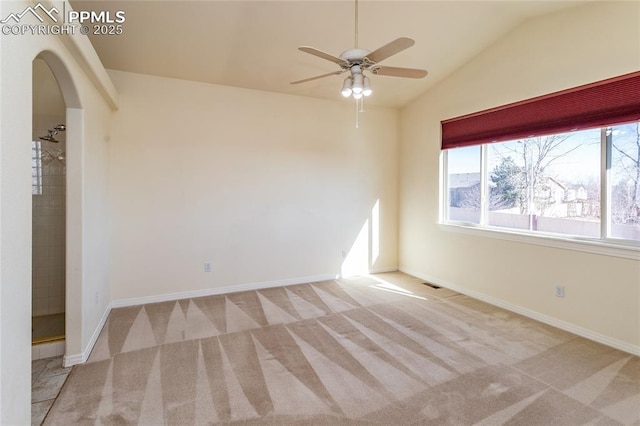 carpeted spare room featuring visible vents, ceiling fan, baseboards, vaulted ceiling, and arched walkways