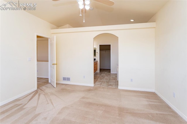 spare room with visible vents, baseboards, ceiling fan, light carpet, and arched walkways