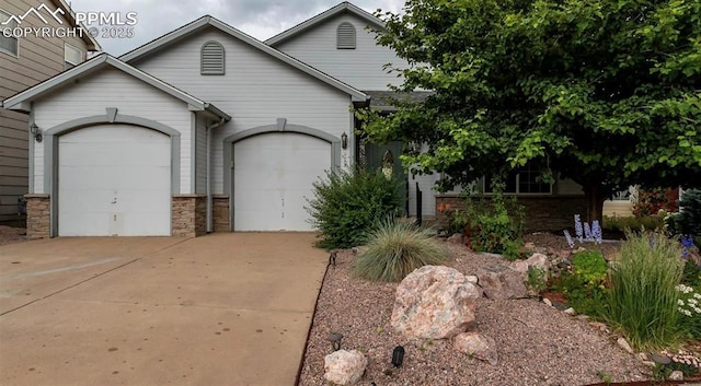 view of front of property featuring stone siding, concrete driveway, and a garage