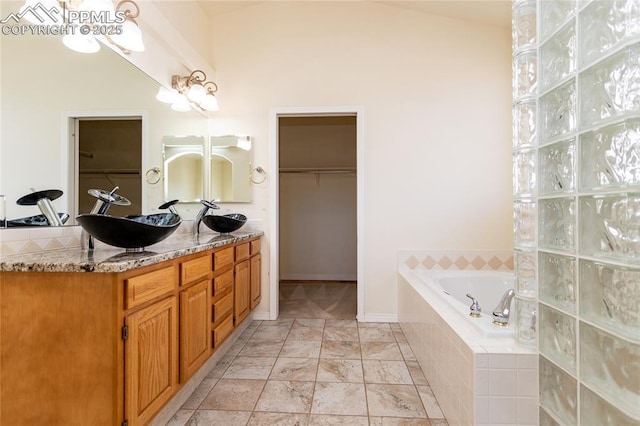 bathroom with double vanity, a walk in closet, a bath, and a sink