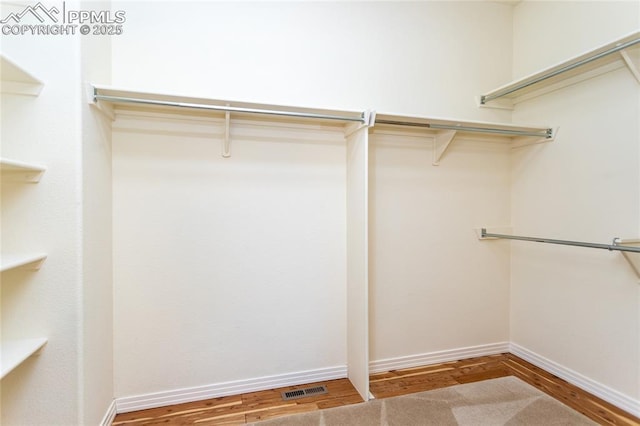 walk in closet with wood finished floors and visible vents