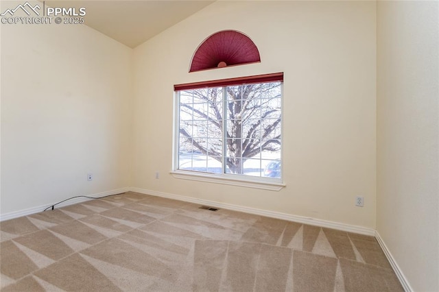 empty room featuring light carpet, baseboards, and lofted ceiling