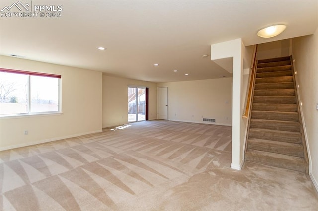 unfurnished room featuring a wealth of natural light, stairway, light carpet, and visible vents