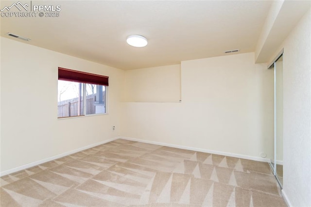 unfurnished room with visible vents, light colored carpet, and baseboards