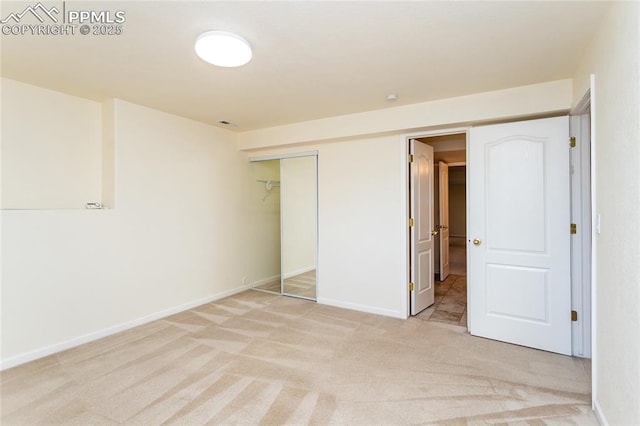 unfurnished bedroom featuring baseboards, a closet, and light carpet