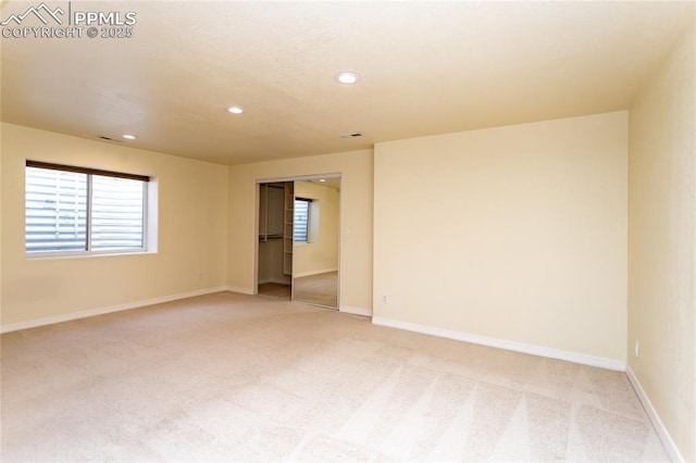 spare room featuring recessed lighting, light colored carpet, and baseboards